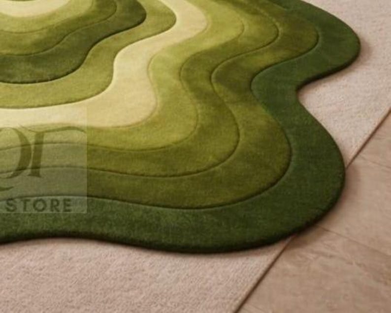 Topographic layered green area rug shown in a spacious classical interior. Wavy organic shape with multiple contour layers in deep and light green tones, resembling terrain elevation. Plush tufted texture, modern artistic floor decor for living rooms or luxury spaces.