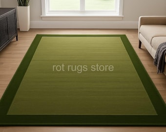 May include: A rectangular green rug with a darker green border. The rug has a textured appearance and the text "rot rugs store" is printed on the rug. The rug is placed on a hardwood floor.
