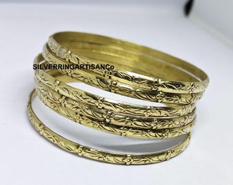 May include: A set of gold-coloured bangles with an embossed floral and leaf pattern. The bangles are stacked on a white surface. The text "SILVERRINGARTISANCO" is visible on the image.