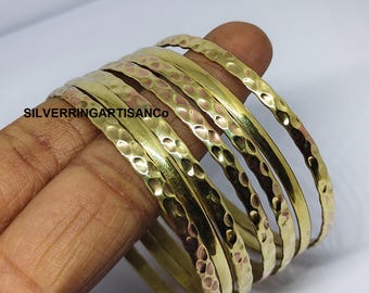 May include: A set of hammered brass bangles. The bangles have a textured surface and a warm, golden colour. The text "SILVERRINGARTISANCO" is visible on the image.