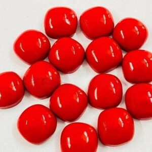 May include: A collection of glossy, bright red, square-shaped beads. The beads are evenly spaced and appear to be made of a smooth, polished material. The beads are a vibrant red color and have a rounded square shape.