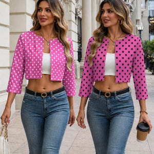 May include: A cropped open-front jacket with three-quarter sleeves, featuring a vibrant pink base with a repeating white polka dot pattern, paired with a white crop top, blue denim jeans, and a black belt with a gold-toned circular buckle.