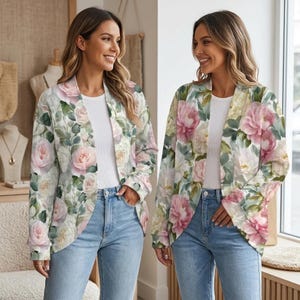 May include: A long-sleeve open-front blazer featuring a soft floral print with pink and white roses and green foliage, worn over a plain white t-shirt and light blue denim jeans. The blazer has a relaxed fit and a notched lapel collar design.