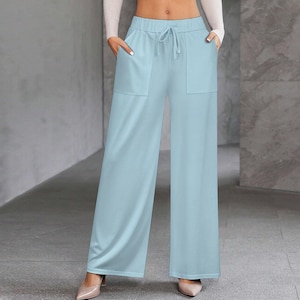 Op de afbeelding: Lichtblauwe palazzo broek met een tailleband met trekkoord en twee voorzakken. De broek met wijde pijpen is gemaakt van een zachte, soepele stof. De broek is effen van kleur en heeft een casual stijl.