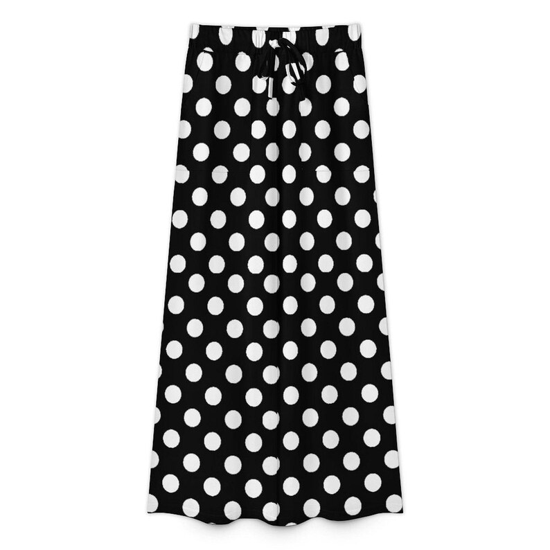 Black skirt with large white polka dots and an adjustable drawstring waistband. The pattern is playful, evoking a retro and stylish vibe.