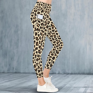 May include: Leopard print leggings with a high waist and a pocket on the right leg. The leggings are tan with brown spots and are paired with white trainers. The leggings are cropped at the ankles.