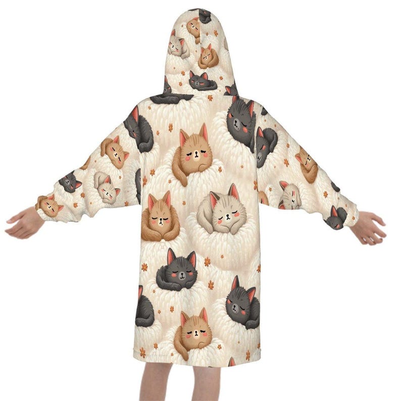 A person wearing a cozy hooded robe with a playful pattern of cartoon cats in brown, gray, and beige shades, set against a cream background. The cats appear fluffy and content, adding a warm, whimsical tone.