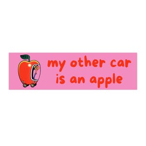 May include: A pink bumper sticker with the text "my other car is an apple" in red. The sticker features a cartoon apple with wheels and a driver inside. The apple car is red with a green leaf.