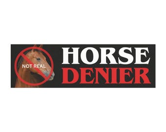 Puede incluir: Una pegatina rectangular negra con las palabras "HORSE DENIER" en blanco y rojo. Una cabeza de caballo marrón está tachada con un círculo rojo, y las palabras "NOT REAL" están debajo.