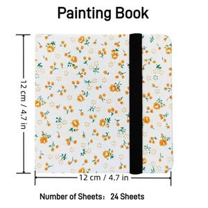 May include: A floral-patterned painting book, 4.7 inches square, with a black elastic band closure. The cover features a white background with small orange flowers and green leaves. The book contains 24 sheets.