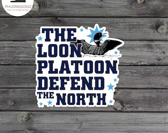 Puede incluir: Una pegatina o imán para coche con el texto "THE LOON PLATOON DEFEND THE NORTH" en blanco y azul marino. Una ilustración en blanco y negro de un colimbo grande está encima del texto. Fondo de madera.