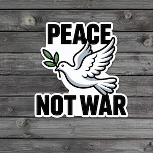 May include: A sticker featuring a white dove with a green olive branch in its beak, with the text "PEACE" above and "NOT WAR" below in bold, black capital letters. The background is a grey wooden surface.