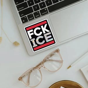 K&ouml;nnte beinhalten: Ein quadratischer Aufkleber mit dem Text "FCK ICE" in fetten wei&szlig;en Buchstaben und einem holografischen "ICE" auf schwarzem Hintergrund, umrahmt von einem roten Rand. Der Aufkleber befindet sich auf einem Laptop, mit Brille und anderen Gegenst&auml;nden in der N&auml;he.