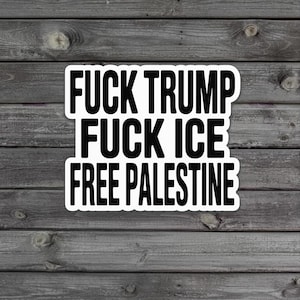 May include: A white sticker with black text that reads "FUCK TRUMP FUCK ICE FREE PALESTINE." The sticker is rectangular with rounded corners and is set against a weathered wood background.