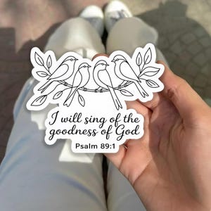 May include: A white sticker featuring a black and white illustration of four birds perched on a branch with leaves. The sticker includes the text "I will sing of the goodness of God" and "Psalm 89:1".