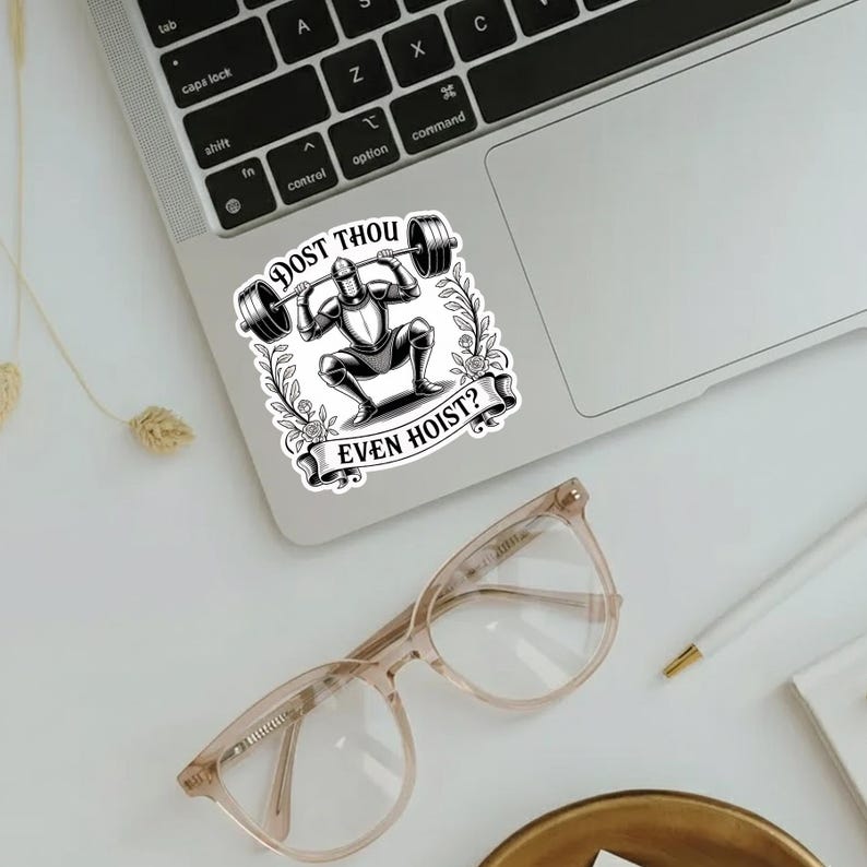 Op de afbeelding: Een zwart-witte sticker met een ridder die een halter optilt. De sticker heeft de tekst "DOST THOU EVEN HOIST?" in een decoratief lettertype. De sticker zit op een laptop.