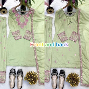 May include: A light green embroidered outfit with matching pants and a scarf. The outfit features intricate pink embroidery on the neckline, sleeves, and borders. The image also shows a pair of black and white patterned shoes.
