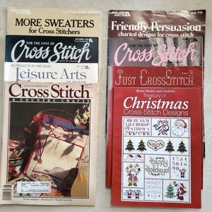 May include: A collection of vintage cross-stitch magazines and pattern booklets featuring titles such as More Sweaters for Cross Stitchers, Friendly Persuasion, For the Love of Cross Stitch, Leisure Arts, and Treasury of Christmas Cross-Stitch Designs.
