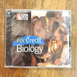 May include: Sealed CD case with the text "For Credit Biology" in blue and white. The case also has the "Pro One" logo and the text "2 CD". The background shows a group of people.