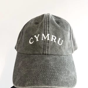 以下が含まれることがあります： 前面に白い刺繍で「CYMRU」の文字が入った、グレーのダメージ加工ベースボールキャップ。 つばがカーブしており、クラウンはしっかりとした構造です。 耐久性のある生地で作られており、ヴィンテージ感があります。