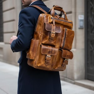 May include: A brown leather backpack with multiple external pockets and a top handle. The bag has brass-coloured buckles and a distressed finish, suggesting a vintage or rugged style. The backpack is designed for carrying items.