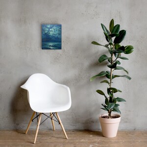 May include: A framed canvas art piece depicting a moonlit seascape in shades of blue and green. The artwork is mounted on a gray wall, with a white chair and a potted plant in the foreground.