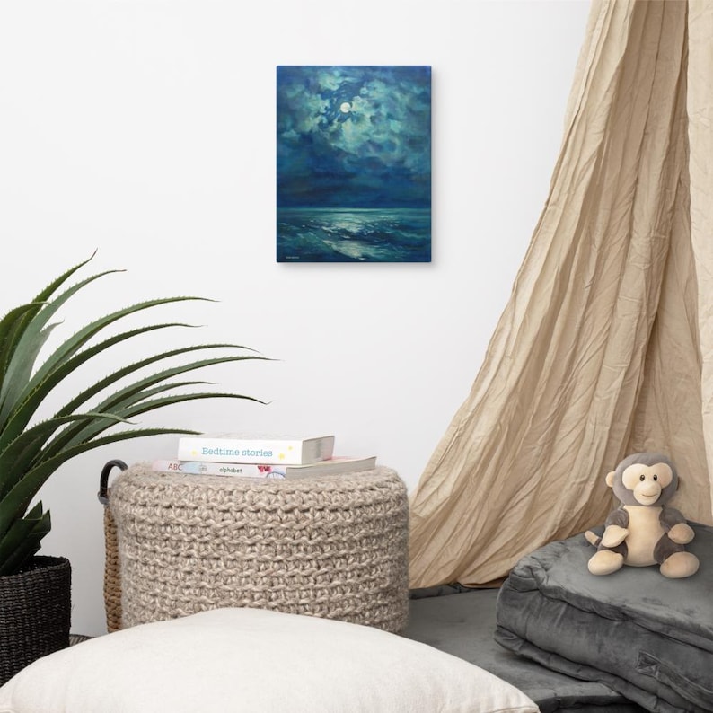 May include: A canvas print of a seascape painting. The artwork depicts a moonlit ocean scene with dark blue and teal hues. The moon is visible in the upper portion of the painting, and the waves are visible in the lower portion. The painting is displayed on a white wall.