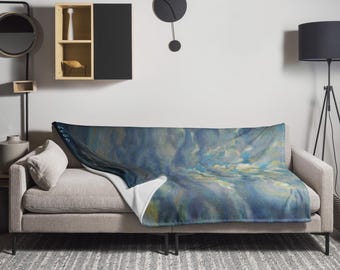 May include: A blue and white throw blanket with an abstract design is draped over a gray sofa. The blanket features a blend of blues, whites, and yellows, creating a soft, artistic look. The text "0947" is visible on the blanket.