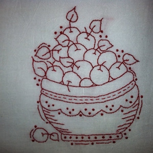 Może przedstawiać: Czerwony haft przedstawiający miskę wypełnioną jabłkami. Miska ma falisty brzeg i kropkowany wzór.