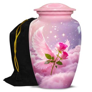 Könnte beinhalten: Eine rosa Urne mit Deckel, verziert mit rosa Engelsflügeln, rosa Rosen und Wolken vor einem lila und rosa Sternenhimmel. Links befindet sich ein schwarzer Samtbeutel mit goldenem Kordelzug.