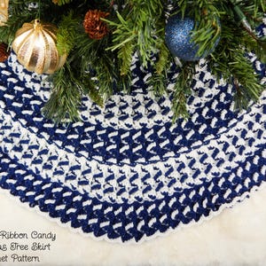 May include: A blue and white crocheted Christmas tree skirt with a textured ribbon candy design. The skirt is made with a combination of single crochet and double crochet stitches. "Crafting Friends Designs" and "Textured Ribbon Candy Christmas Tree Skirt Crochet Pattern" are written on the white background.