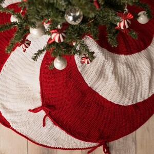 May include: A red and white crocheted Christmas tree skirt with a candy cane swirl design. The skirt has two ties on each side.