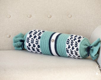 May include: A crocheted bolster pillow with a blue, white, and green striped pattern. The pillow is on a light beige couch.