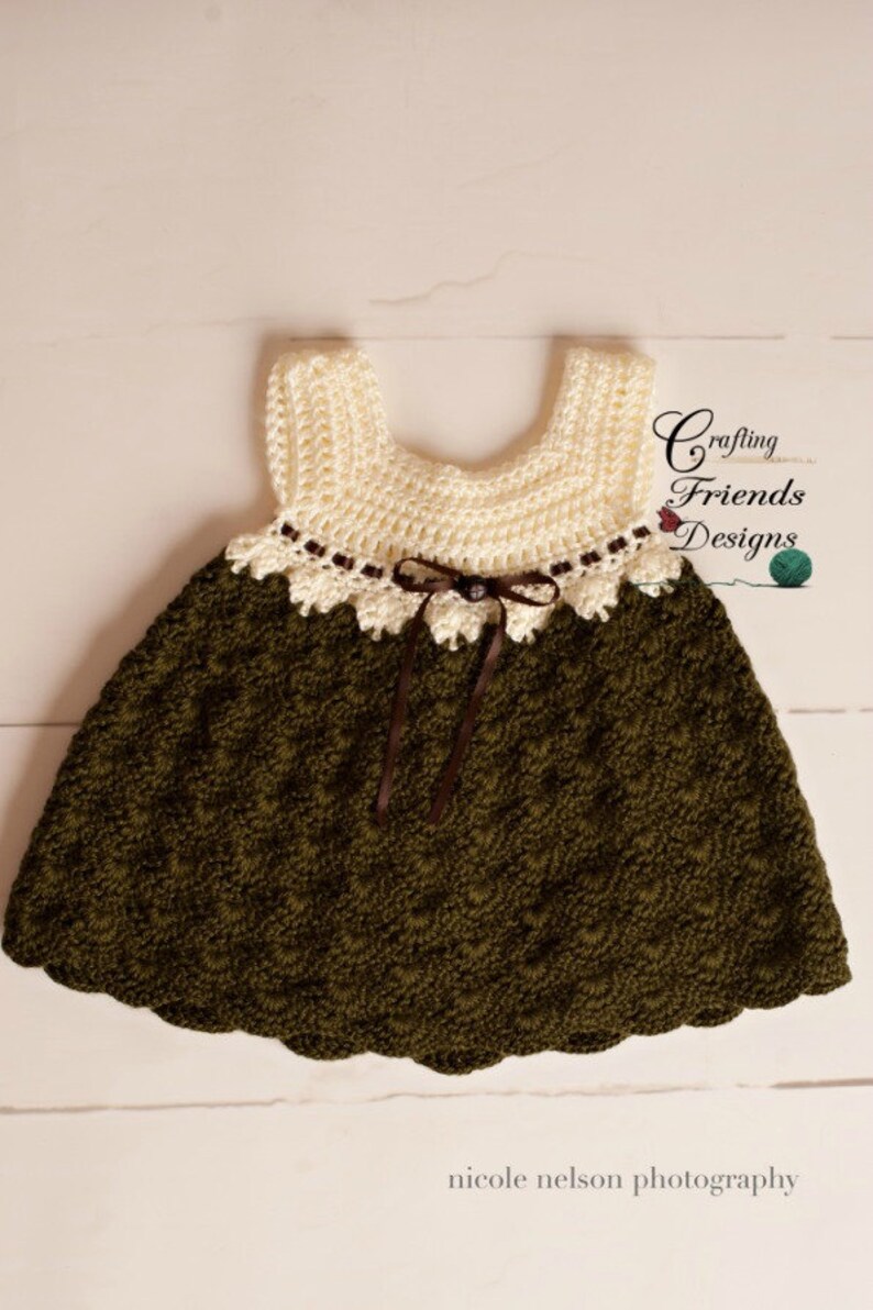 Peut inclure: Une robe de b&eacute;b&eacute; en crochet de couleur marron et blanche. La robe a un ourlet festonn&eacute; et un ruban marron nou&eacute; &agrave; la taille. La robe est r&eacute;alis&eacute;e avec un point textur&eacute; et a une d&eacute;licate bordure en dentelle autour de l'encolure.