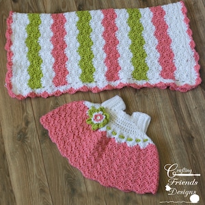 May include: A crocheted baby blanket and dress set in pink, white and green. The blanket has a scalloped edge and the dress has a flower embellishment.