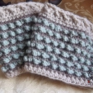 May include: Two crocheted arm warmers with a textured pattern in shades of gray and light blue. The arm warmers are made with a bobble stitch and have a contrasting gray border.