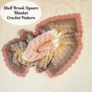 May include: A crocheted blanket in shades of pink, white, tan, and brown with a scalloped edge. The blanket has a square pattern and the text "Shell Brook Square Blanket Crochet Pattern" is in the upper left corner.