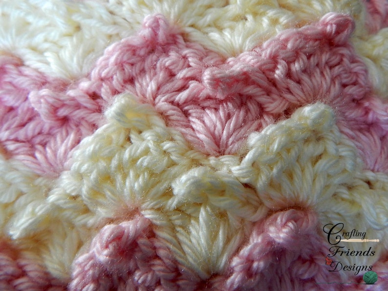 May include: Close-up of a crocheted fabric with a pink and white striped pattern. The fabric is made with a textured stitch that creates a wave-like effect.