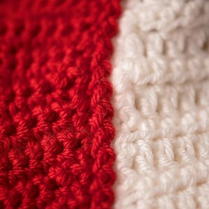 May include: Close-up of a red and white crocheted fabric. The fabric is made with a simple stitch and has a smooth texture.