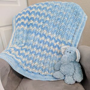 May include: A blue and white crocheted baby blanket with a blue plush elephant toy sitting on top of it.