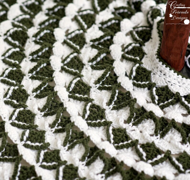 May include: Close-up of a crocheted doily with a white and green geometric pattern. The doily is made with a delicate stitch and has a scalloped edge.