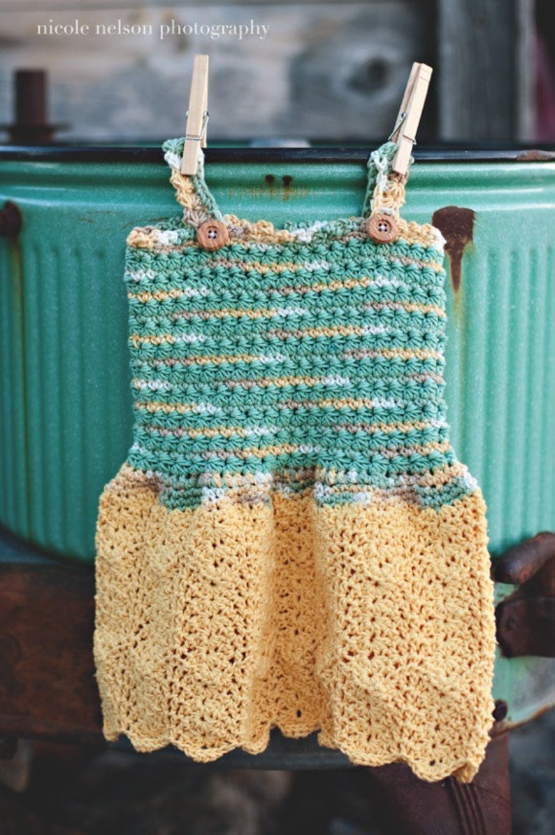 May include: A crocheted baby dress with a green and yellow striped bodice and a yellow crochet skirt. The dress is hanging on a clothesline with wooden clothespins.