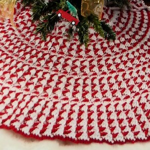 May include: A red and white crocheted Christmas tree skirt with a scalloped edge.