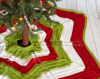 Puede incluir: Una falda de árbol de Navidad de ganchillo en rojo, blanco y verde con un diseño de estrella. La falda está hecha con un punto texturizado y tiene flecos alrededor de los bordes.