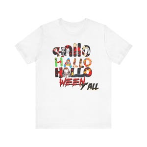 May include: A white short-sleeve t-shirt featuring a graphic print on the chest. The design displays the text "HALLO HALLO HALLO WEEN Y'ALL" with each letter filled with various horror movie character imagery, including Pennywise and Ghostface.