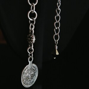 Op de afbeelding: Een witte keramische mok met een zwart handvat en de tekst "But First, Coffee" in een vetgedrukte, zwarte letter. De mok staat op een houten oppervlak. De mok is ongeveer 10 cm hoog.