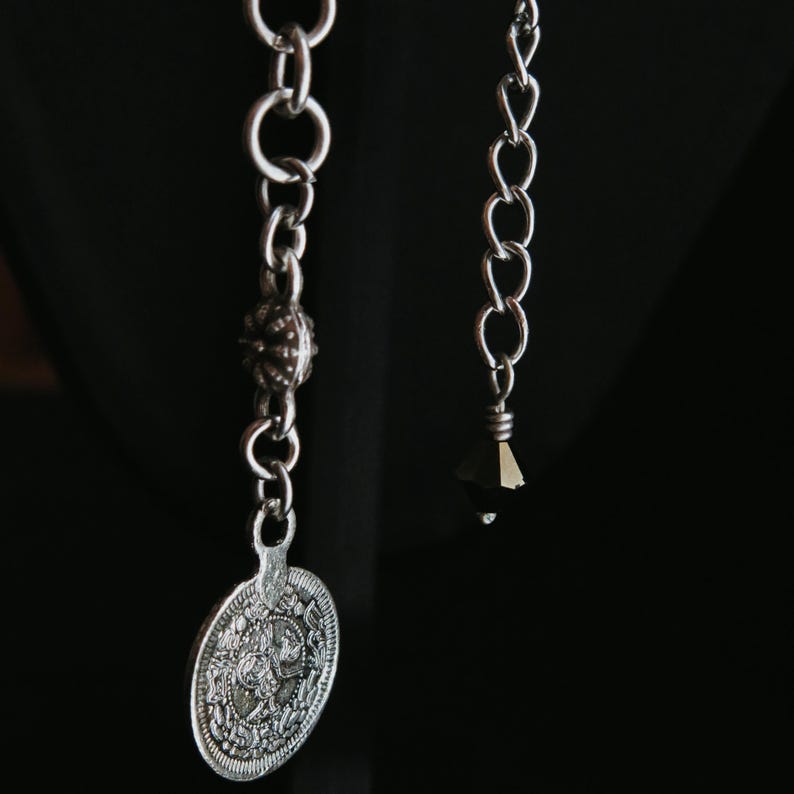 Op de afbeelding: Een witte keramische mok met een zwart handvat en de tekst "But First, Coffee" in een vetgedrukte, zwarte letter. De mok staat op een houten oppervlak. De mok is ongeveer 10 cm hoog.