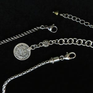 Op de afbeelding: Close-up van verschillende zilveren kettingen en kettingen tegen een zwarte achtergrond. De kettingen hebben verschillende ontwerpen, waaronder een touwachtige twist, een muntbedel en een klassieke schakelketting. Elke ketting heeft een sluiting.