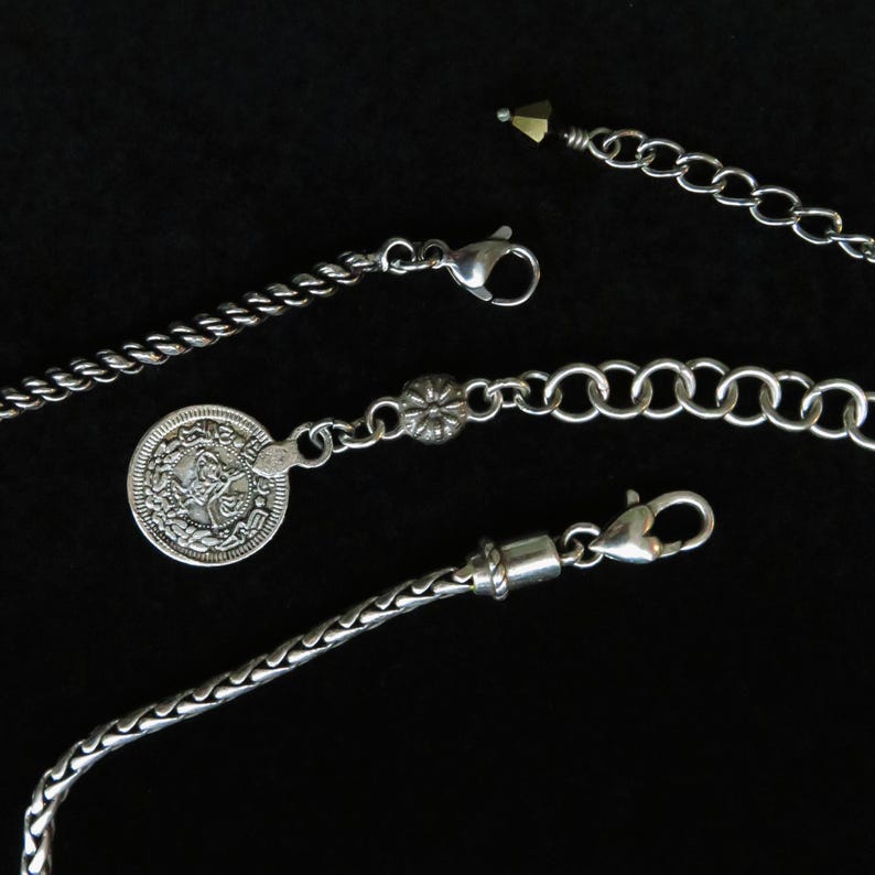 Op de afbeelding: Close-up van verschillende zilveren kettingen en kettingen tegen een zwarte achtergrond. De kettingen hebben verschillende ontwerpen, waaronder een touwachtige twist, een muntbedel en een klassieke schakelketting. Elke ketting heeft een sluiting.