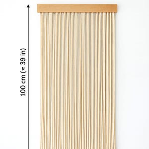 May include: Beige rope curtain, 39 inches long and 20 inches wide, with a wooden header. The curtain is made of numerous vertical ropes, creating a textured, natural look. The studio name is visible at the bottom.